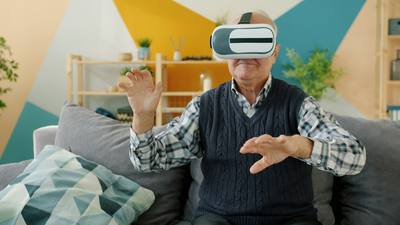 Senior man in casual clothes is using virtual reality glasses and gesturing