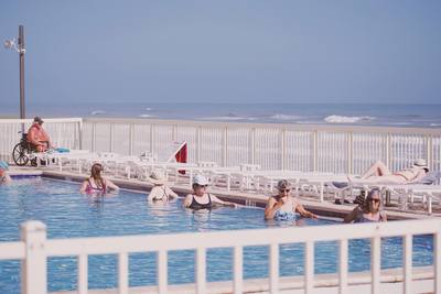 old people in oceanfront swimming pool prepare to do water aerobics