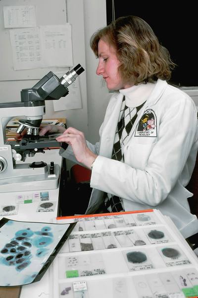 A female Caucasian scientist examining pap smears under the microscope.